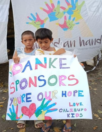 Kinder in den Slums halten ein selbst gemaltes Plakat: Danke Sponsors – You're our Hope
